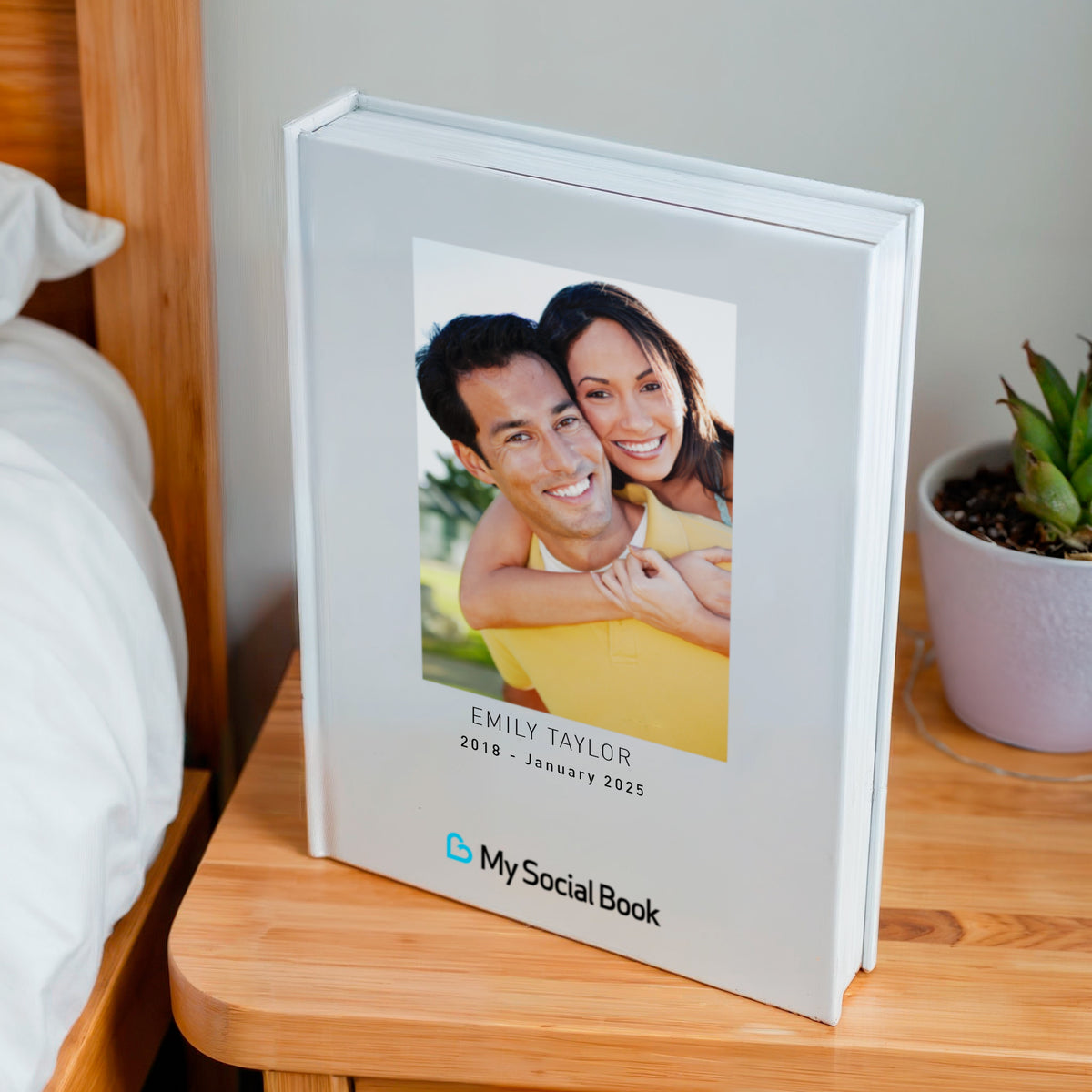 Dropbox photo book — hardcover photo book with a couple portrait cover, displayed on a bedside table, evoking private family memories